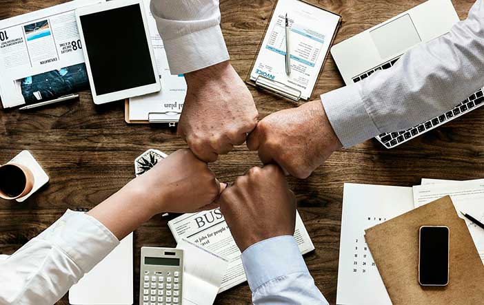 Brazos que chocan el puño en señal de éxito sobre una mesa de trabajo